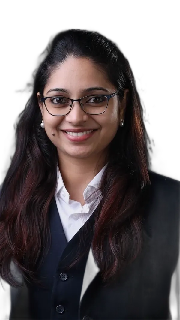 Reena in a navy suit and glasses, smiling